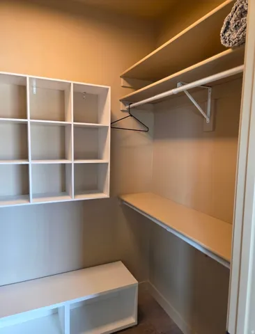 Built-in shelving, integrated hanging rod, and a built-in bench provide organized storage solutions