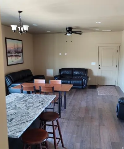 Wood-finish flooring, recessed lighting, ceiling fan, and a kitchen island with a stone countertop