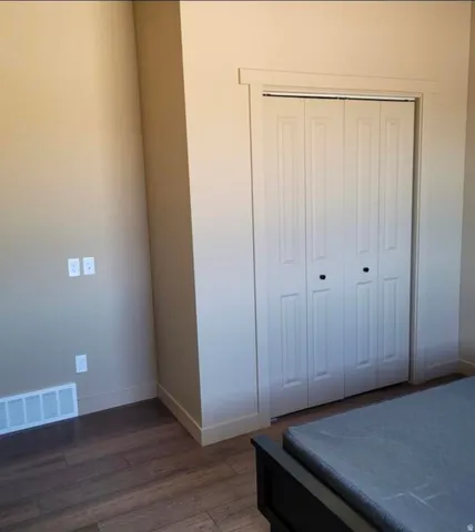 Wood-finish flooring with white trim, featuring a bifold closet door with black hardware