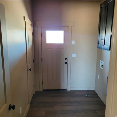 Entryway featuring wood-finish flooring, a door with an integrated window, and a built-in dark wood cabinet