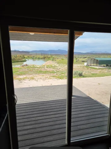Sliding glass doors opening to an outdoor deck, a prominent body of water, and distant mountains