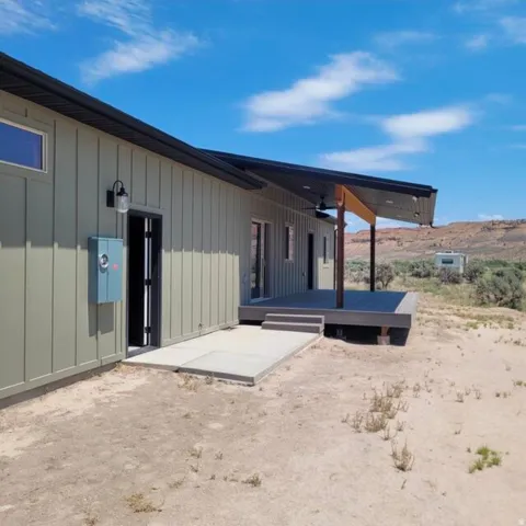 Modern architecture featuring board and batten siding, a covered deck, and an exterior ceiling fan