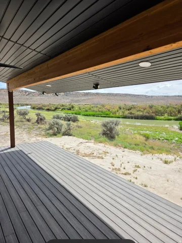 Expansive outdoor deck with composite decking, featuring a wood-finish support beam and integrated ceiling lighting