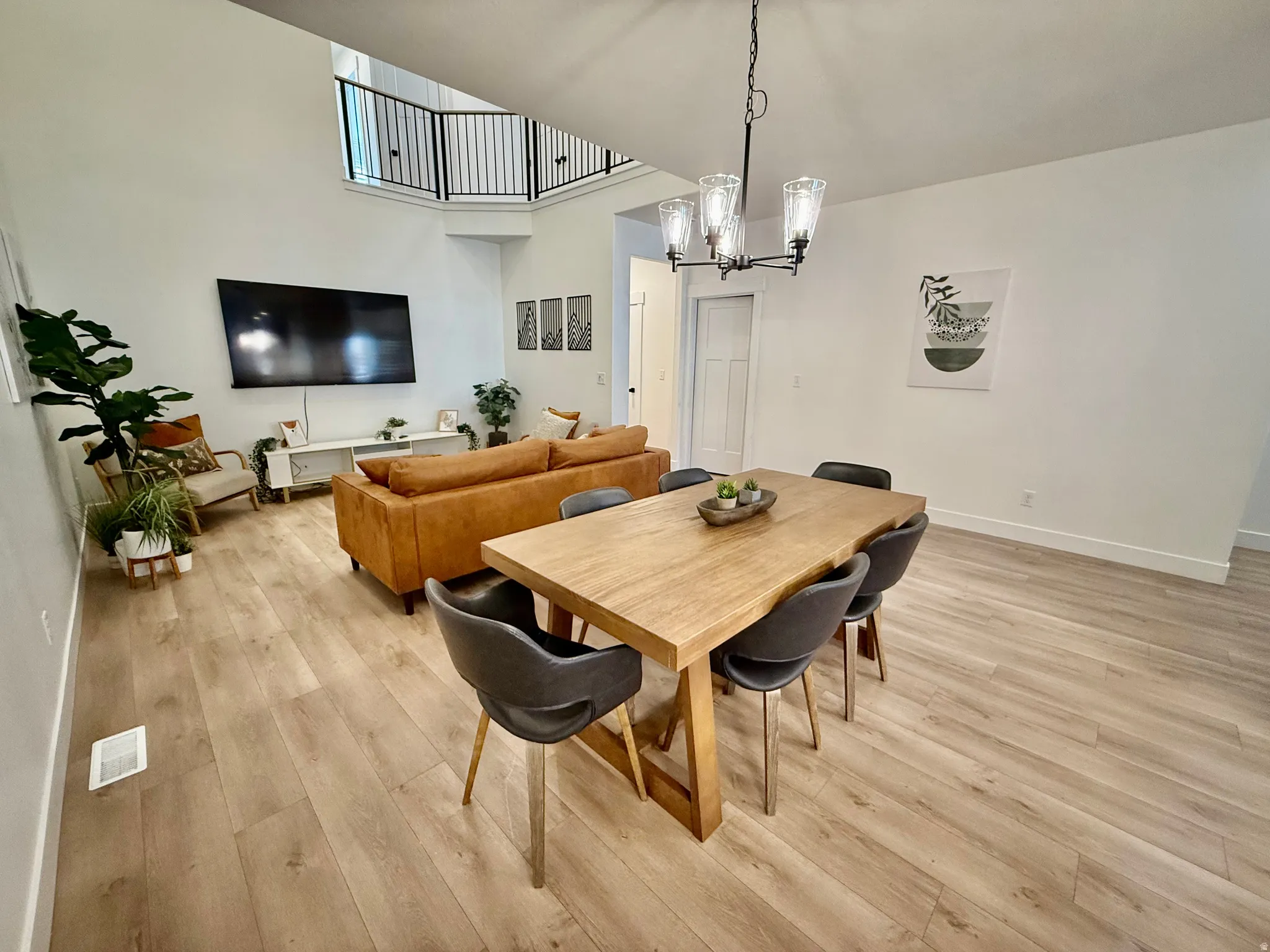 Open-concept living space featuring high ceilings, wood-finish flooring, and a modern chandelier