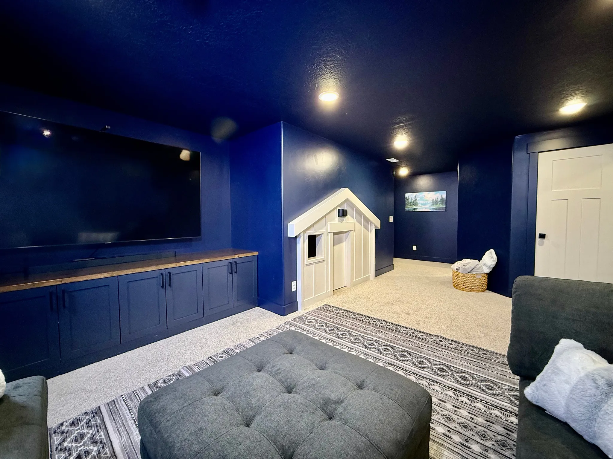 Built-in media console with wood-finish countertop, recessed lighting, and a white panel door