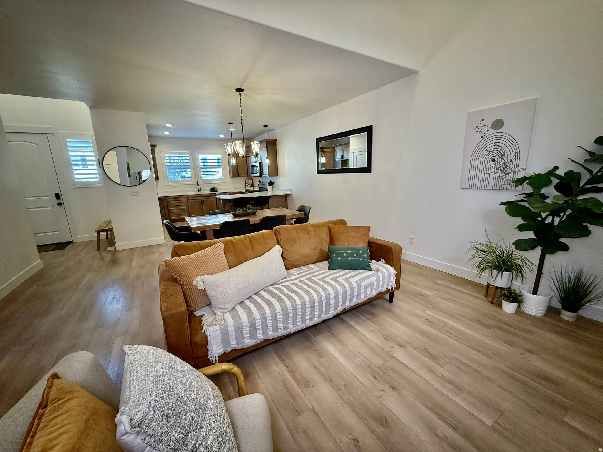 Vaulted ceilings, wood-finish flooring, white plantation shutters, dark wood cabinetry, and pendant lighting fixtures