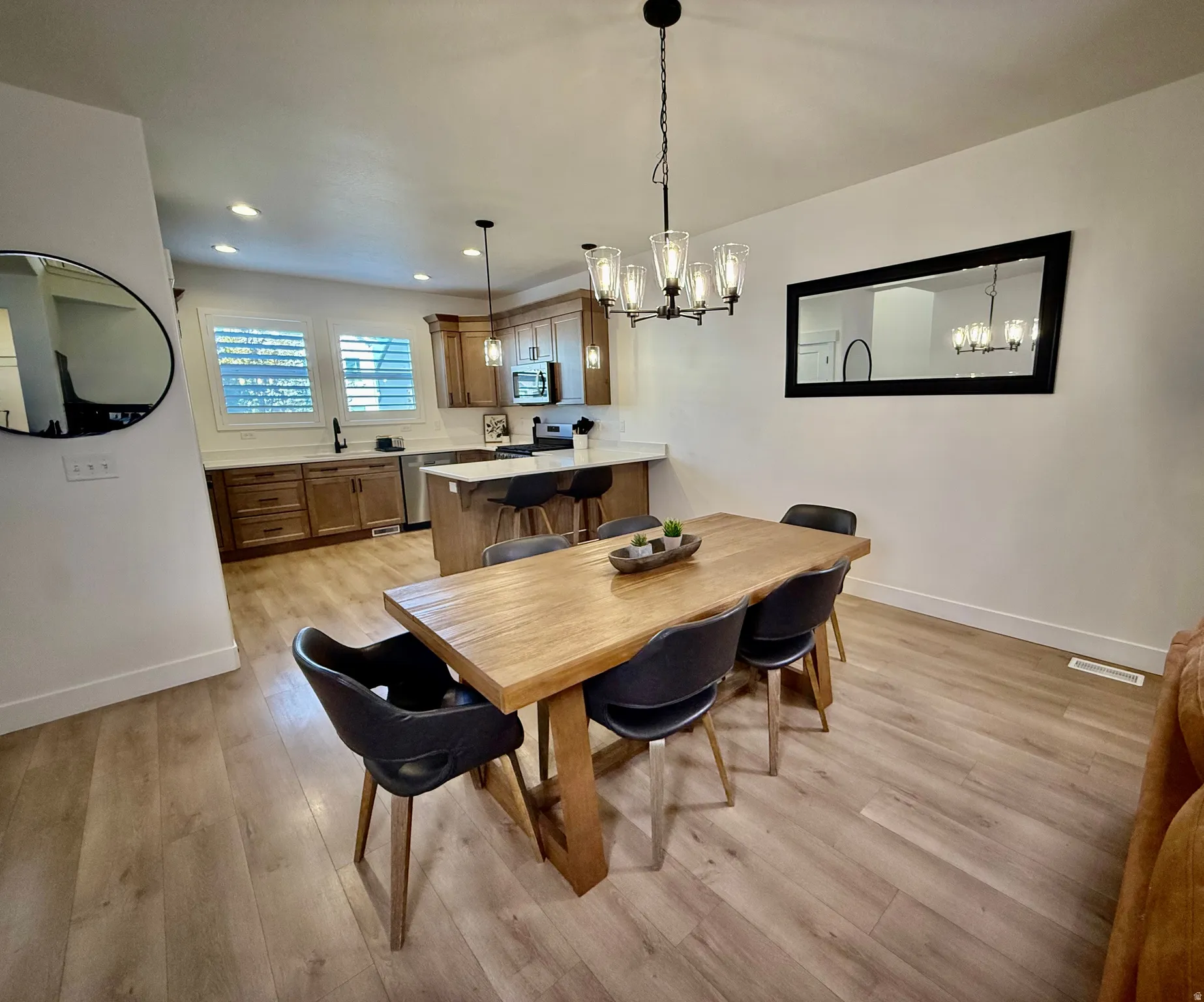 Open-concept living space featuring wood-finish flooring, recessed lighting, and a modern chandelier