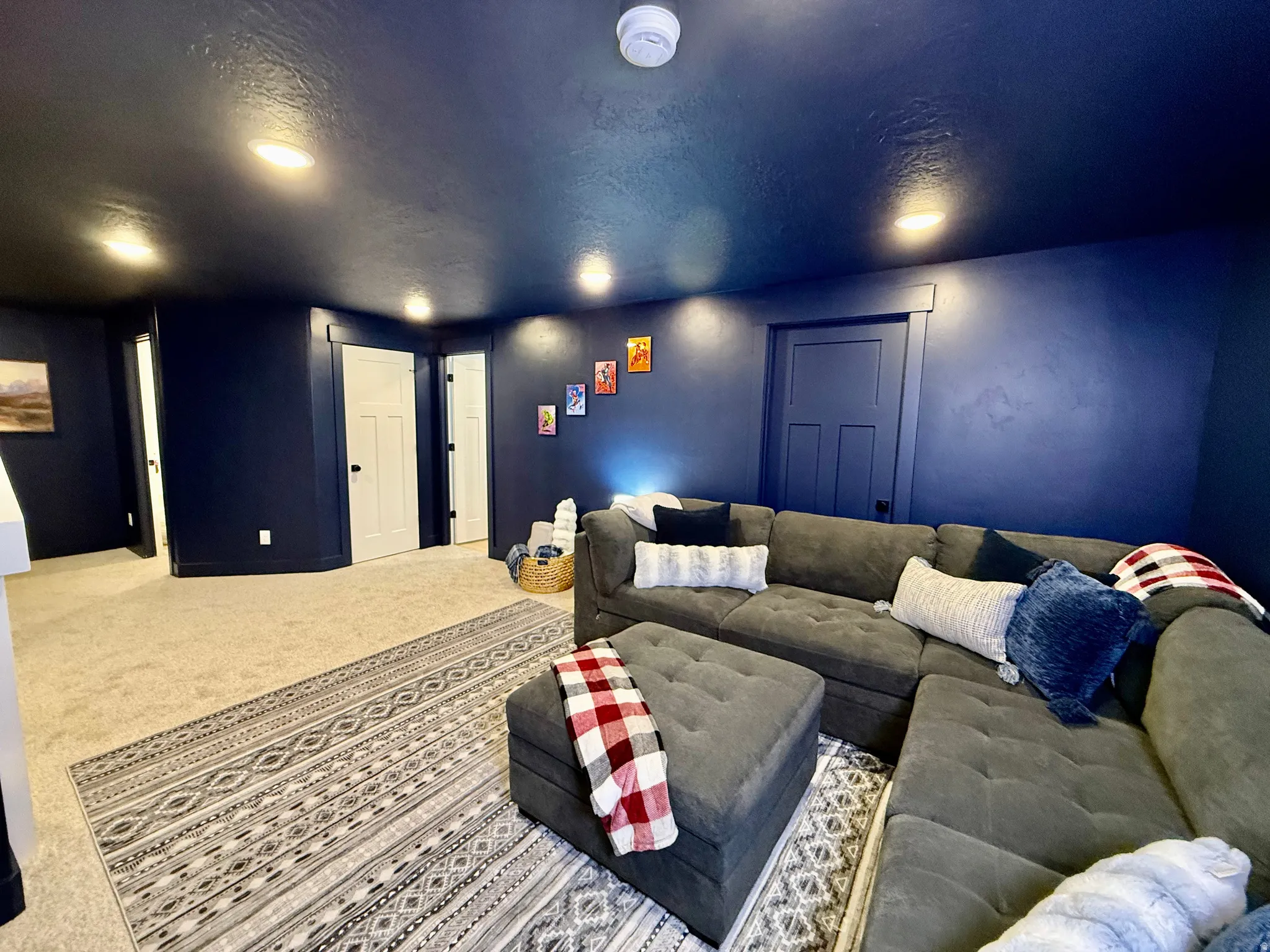 Recessed lighting illuminates deep blue walls and a carpeted floor