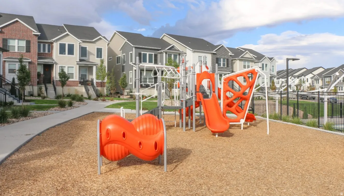 Mountain Ridge tot lot with wood chip surfacing, multiple slides, climbing structures, and a dedicated pathway