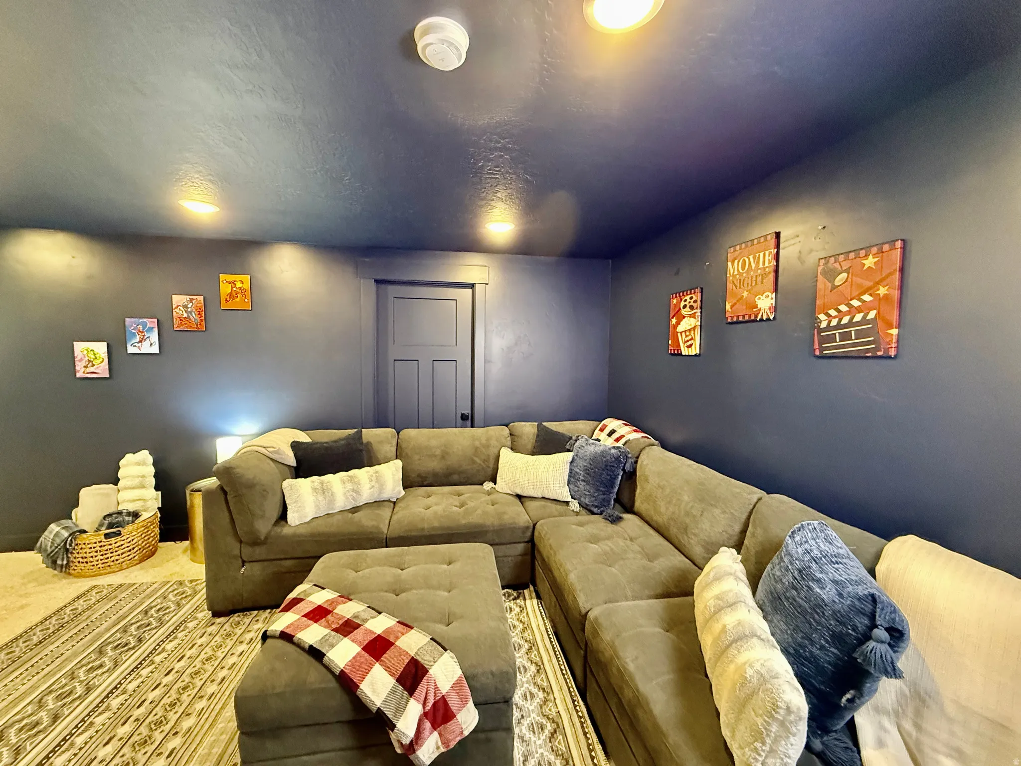 Recessed lighting illuminates the room with dark blue walls, complemented by a panel door and light-colored carpet
