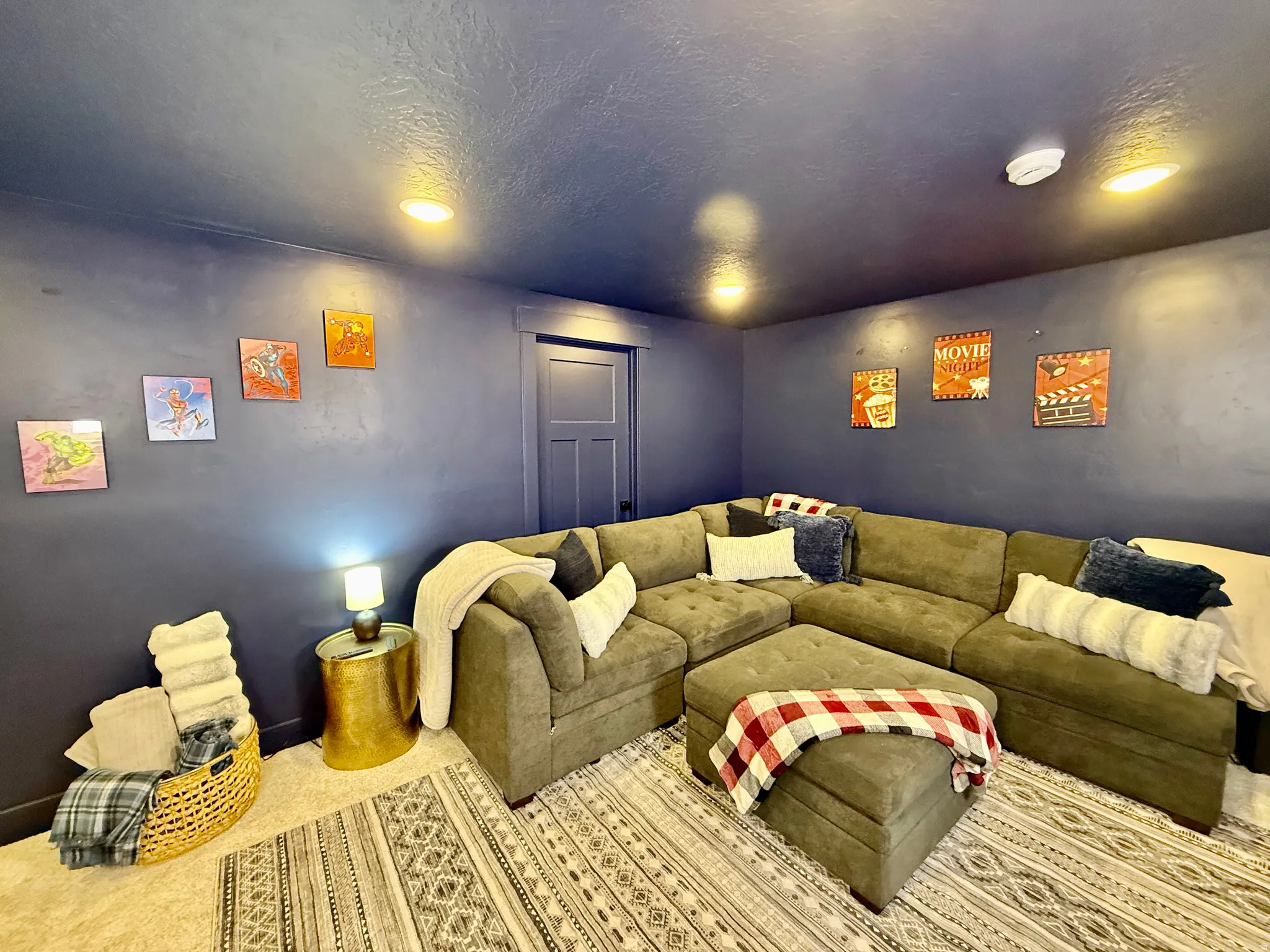 Recessed ceiling lighting illuminates a room with a textured ceiling, a deep blue wall finish, and a paneled door