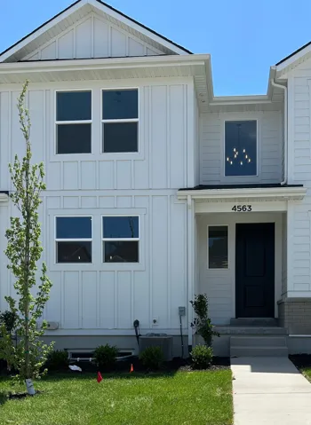 Modern exterior with white vertical siding, prominent gables, and a dark entry door