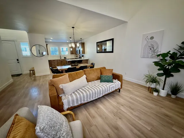 Vaulted ceilings, wood-finish flooring, white plantation shutters, dark wood cabinetry, and pendant lighting fixtures