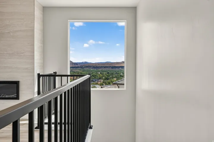 Black metal railing, rectangular window, light-toned wall, wall-mounted fireplace, and light-toned tile surround