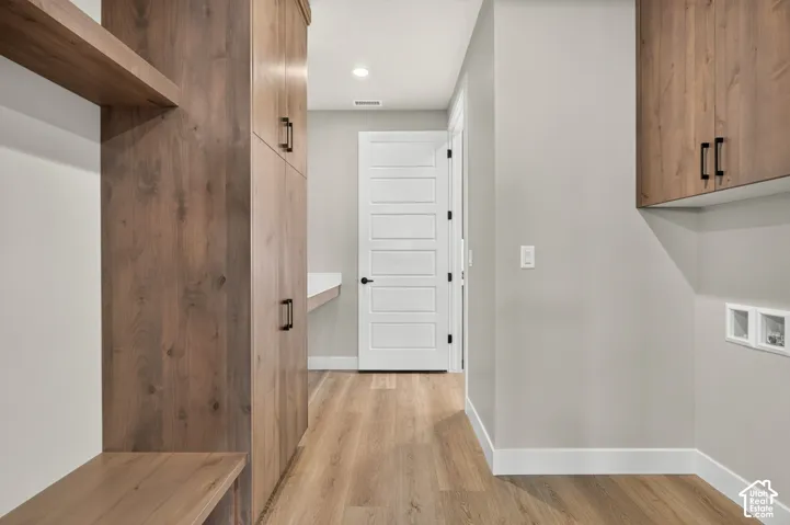 Hallway featuring wood-finish flooring, built-in wood-look cabinetry, a built-in bench, and a white paneled door