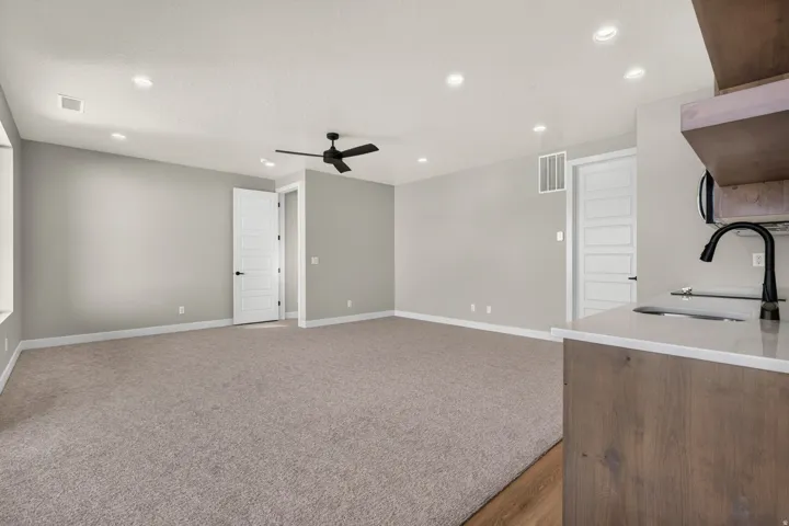 Recessed lighting, ceiling fan, neutral wall color, carpeted flooring, and a kitchen counter with a sink