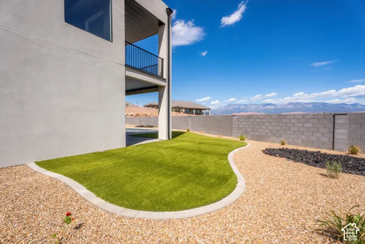 Contemporary exterior with a balcony, synthetic turf lawn, and gravel landscaping