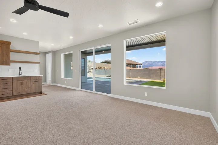 Recessed lighting, wood-finish cabinetry, sliding glass door, modern ceiling fan, and mountain scenery