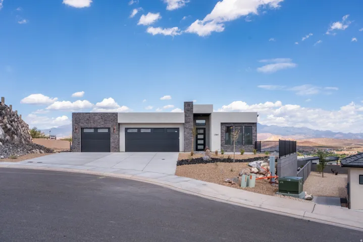 Modern architecture featuring a two-car garage, stone and stucco exterior, and multi-pane front entry door