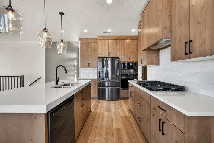 Modern kitchen featuring wood-finish cabinetry, white countertops, stainless steel appliances, and a gas range