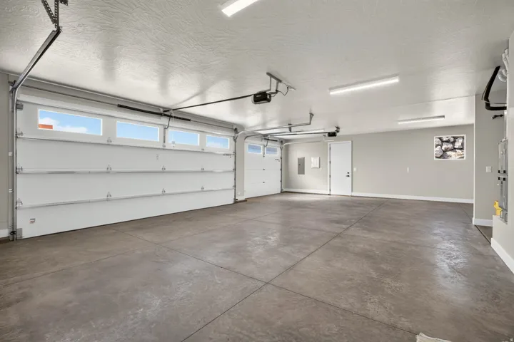 Spacious garage featuring a concrete floor, two white garage doors with upper windows, and flush-mounted ceiling lights