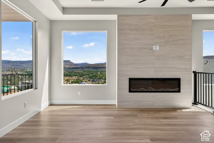 Expansive windows, wood-finish flooring, and a modern fireplace with a tiled surround