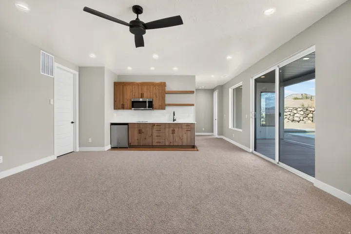Built-in wet bar with wood-finish cabinetry, stainless steel sink, and open shelving