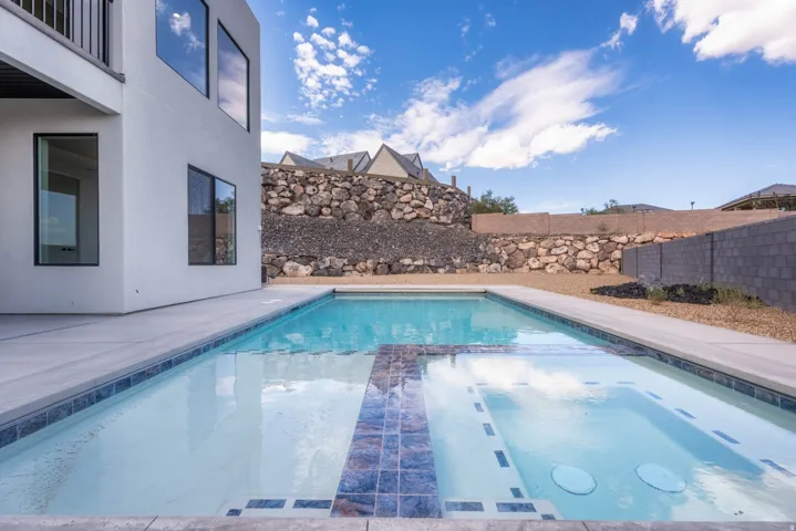 Expansive outdoor space featuring a swimming pool, integrated spa, and concrete decking