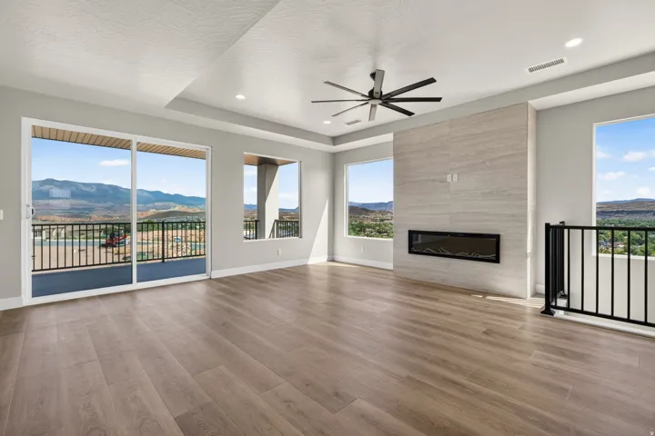 Spacious room featuring wood-finish flooring, a contemporary fireplace with a stone surround, recessed lighting, and a ceiling fan
