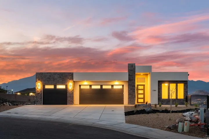 Modern exterior featuring stone accents, a multi-panel front door, and a two-car garage