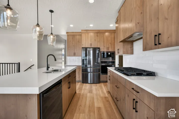 Modern kitchen featuring wood-finish cabinetry, white countertops, stainless steel appliances, and a gas range