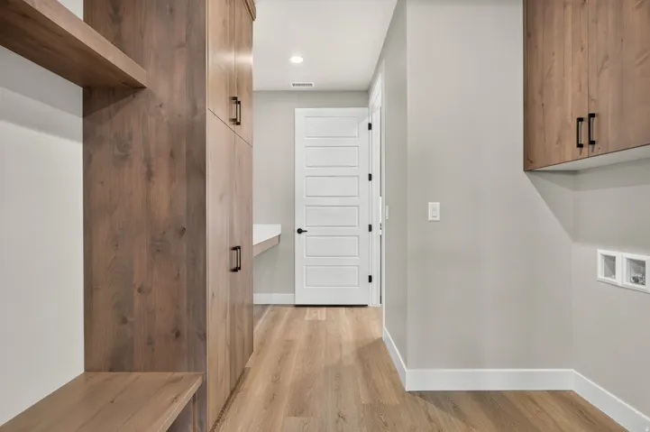 Hallway featuring wood-finish flooring, built-in wood-look cabinetry, a built-in bench, and a white paneled door