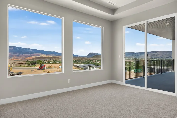Recessed lighting, tray ceiling, sliding glass door to a balcony, large windows, and neutral carpeting
