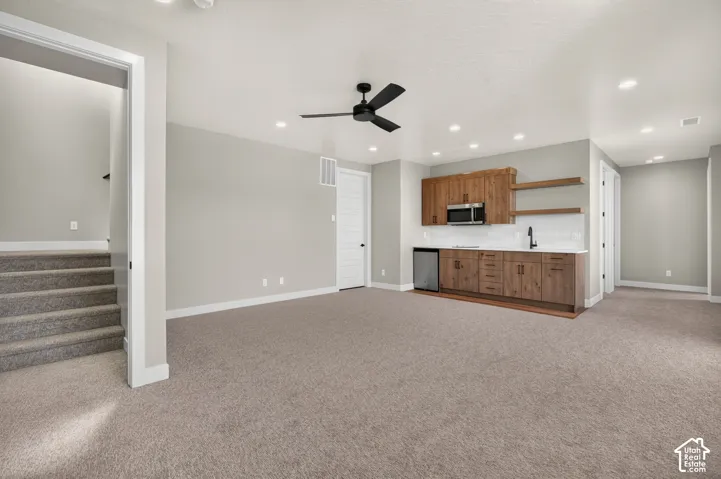 Recessed lighting, wood-finish cabinetry, built-in microwave, white subway tile backsplash, and a ceiling fan