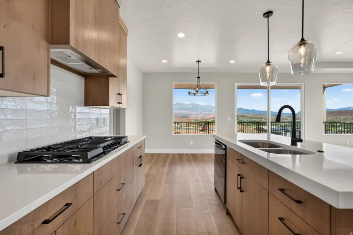 Kitchen featuring wood cabinetry, white countertops, a gas range, and a dual basin sink with a matte black faucet