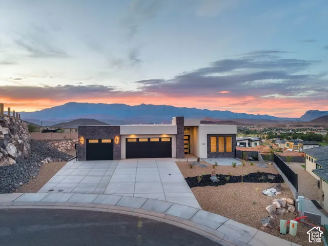Modern architectural design with a flat roofline, stone veneer accents, and a large concrete driveway