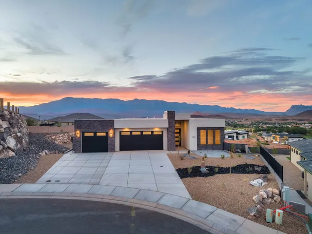 Modern architectural design with a flat roofline, stone veneer accents, and a large concrete driveway