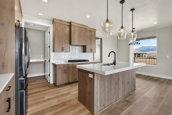 Kitchen featuring a large island with sink and integrated seating, wood-finish flooring, white countertops, and wood cabinetry
