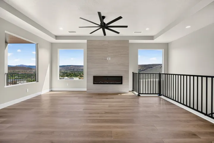 Recessed lighting, wood-finish flooring, contemporary fireplace, black metal railing, and exposed beam ceiling