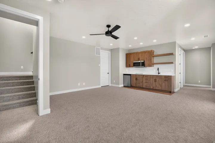 Recessed lighting, wood-finish cabinetry, built-in microwave, white subway tile backsplash, and a ceiling fan