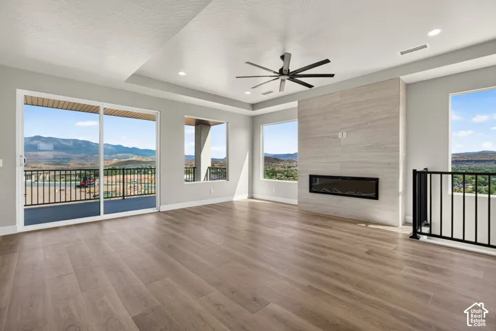 Spacious room featuring wood-finish flooring, a contemporary fireplace with a stone surround, recessed lighting, and a ceiling fan