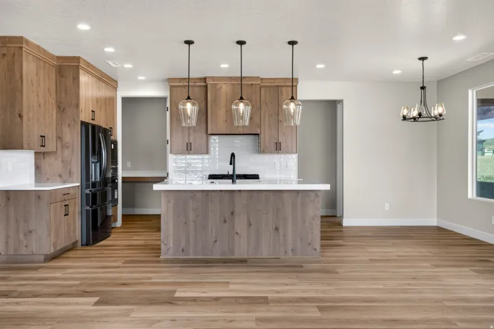 Wood-finish flooring throughout, kitchen island with pendant lighting, built-in cabinetry, white tile backsplash, and recessed lighting