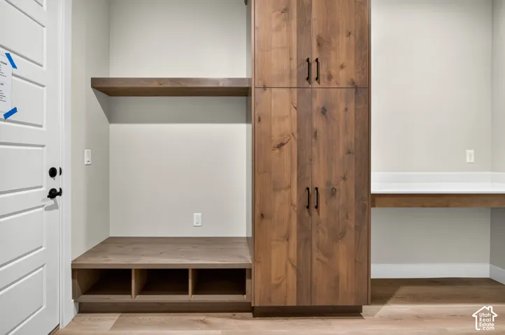 Custom wood-finish built-in cabinetry with multiple storage compartments and open shelving, featuring a lower bench unit with three cubbies and upper cabinet doors with metal hardware