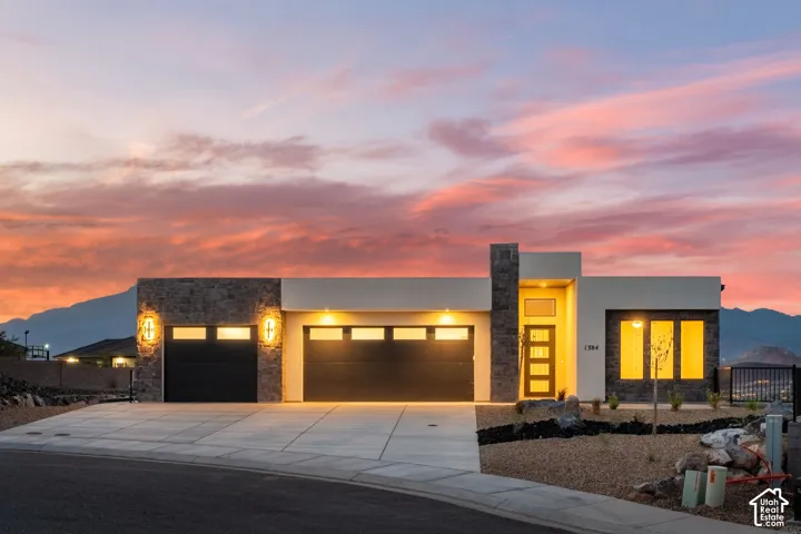 Modern exterior featuring stone accents, a multi-panel front door, and a two-car garage