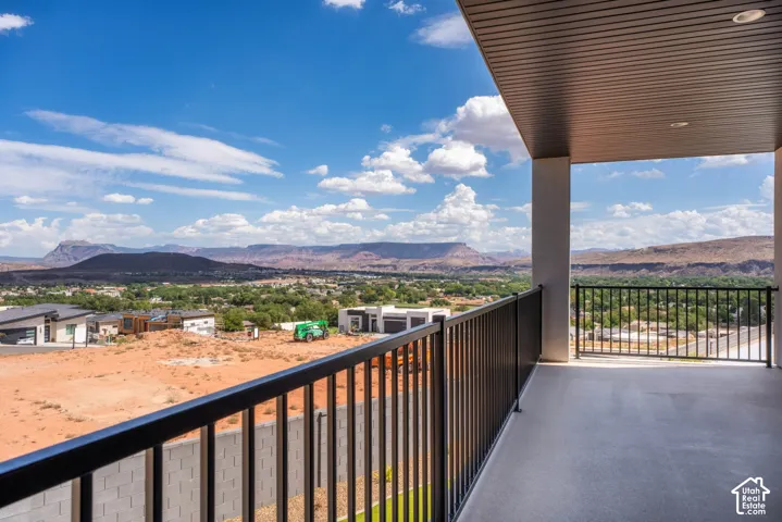 Covered outdoor balcony with a black metal railing, offering expansive desert and mountain scenery
