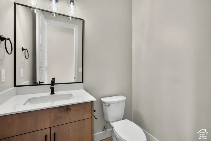 Wood-finish vanity with white countertop, undermount sink, and matte black faucet