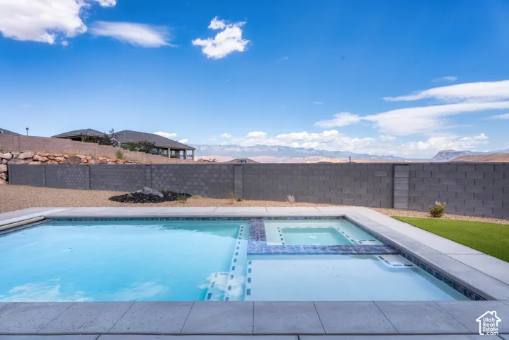 In-ground swimming pool with integrated spa, concrete coping, and decorative tile accents