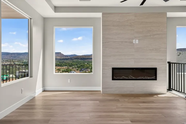 Expansive windows, wood-finish flooring, and a modern fireplace with a tiled surround