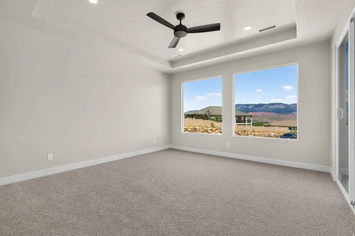 Recessed lighting, tray ceiling, ceiling fan, large windows, and carpeted flooring