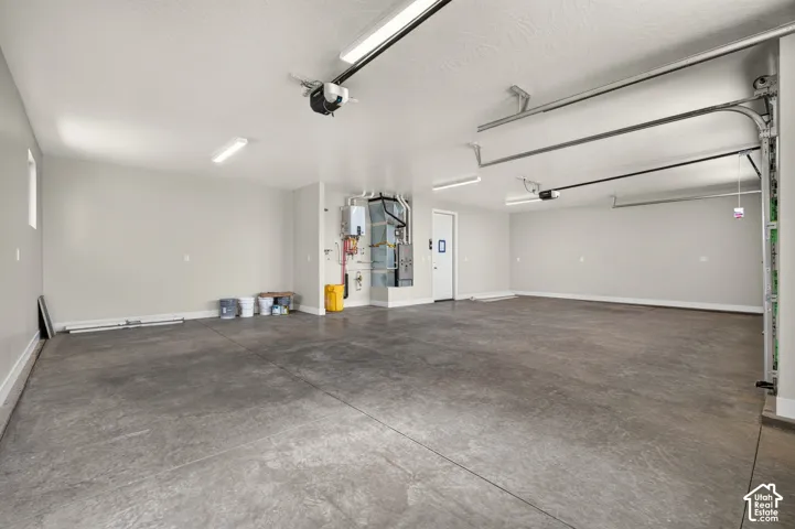 Spacious garage with concrete flooring, overhead lighting, and an accessible side entry door
